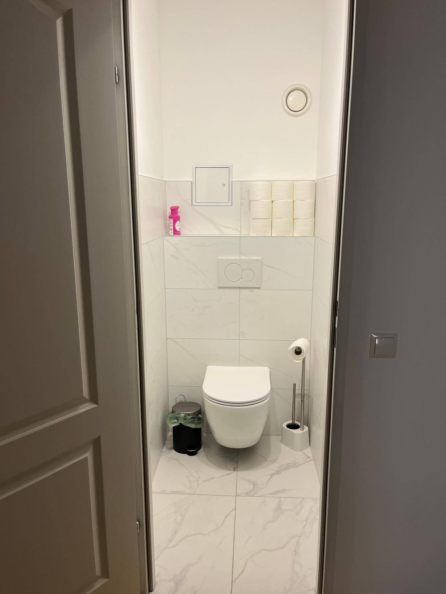 Kleines, modernes Gäste-WC mit wandhängender Toilette und weißen Fliesen.
