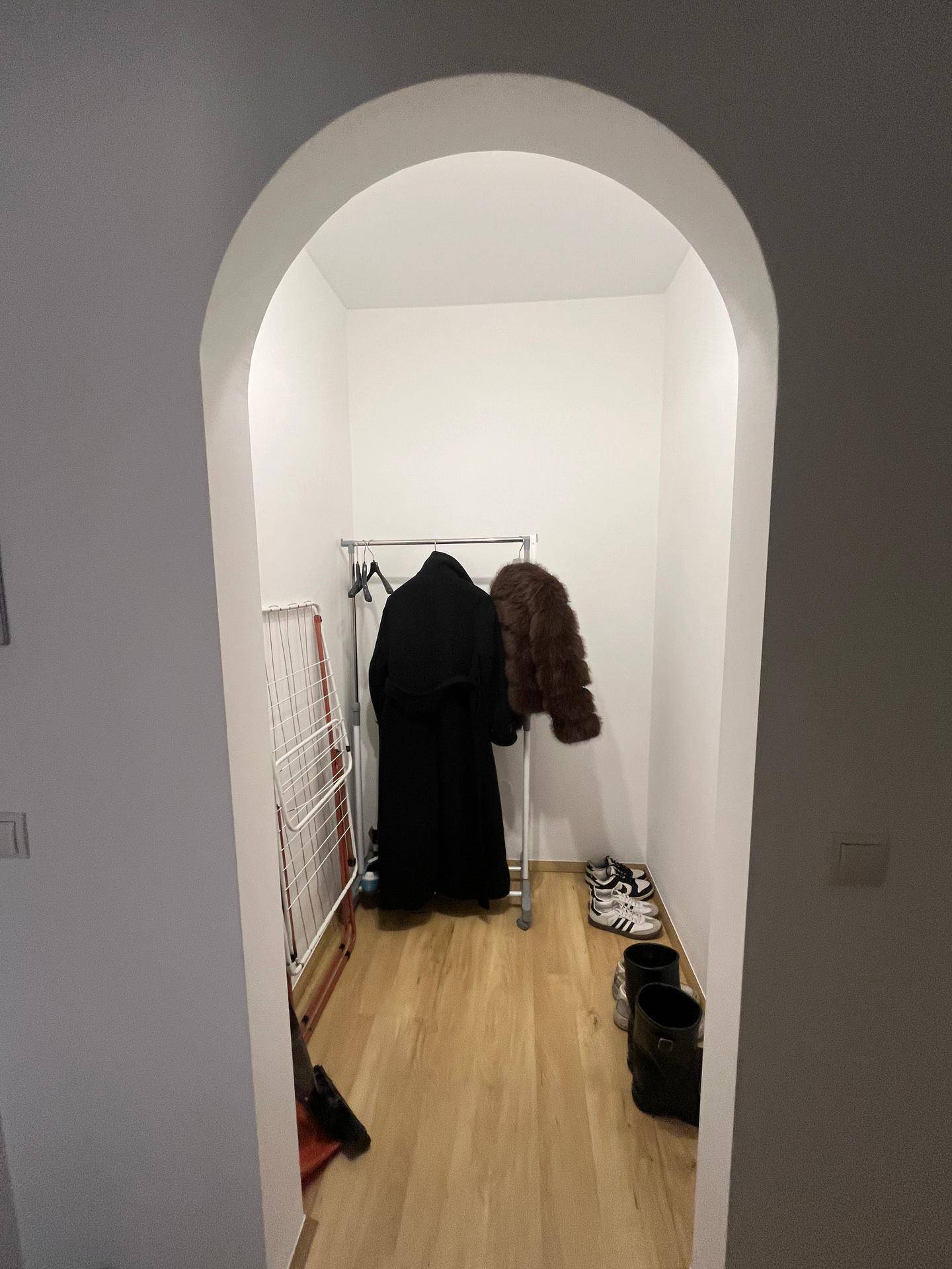 Heller Flur mit einem Bogen und einer Nische, die als Garderobe genutzt wird.