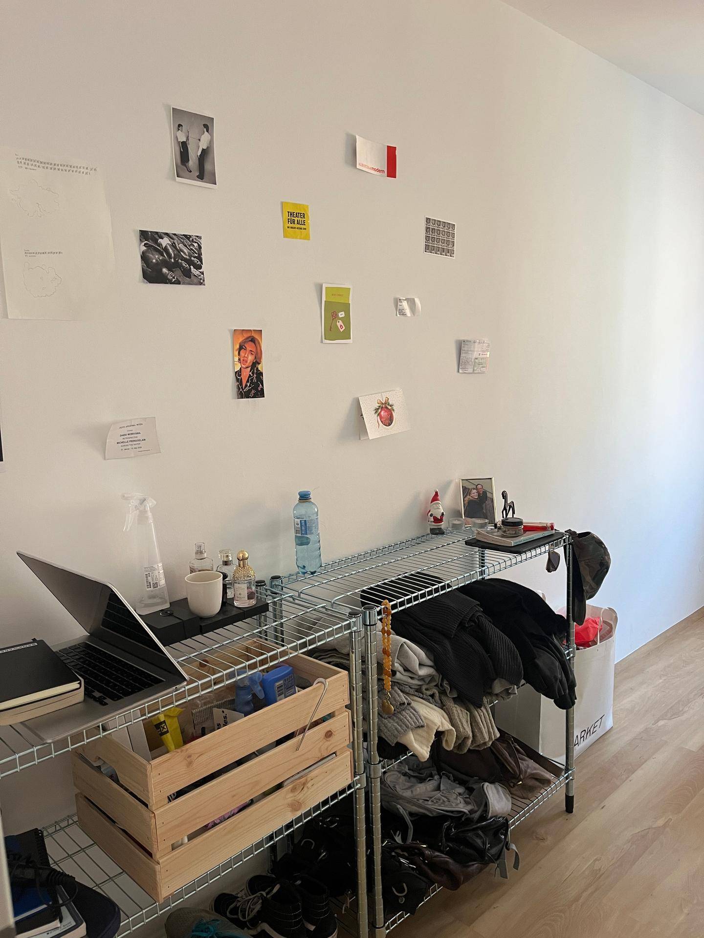 Regal mit persönlichen Gegenständen und Dekoration an einer weißen Wand im Schlafzimmer.