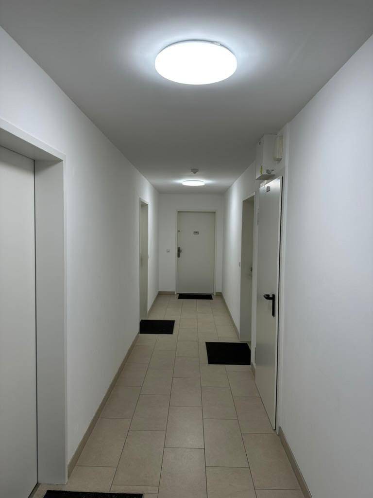 Langer, heller Flur mit Fliesenboden und mehreren Türen zu den einzelnen Wohneinheiten.