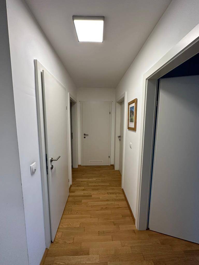 Heller Flur mit Holzboden und mehreren weißen Türen, der zu den verschiedenen Zimmern führt.