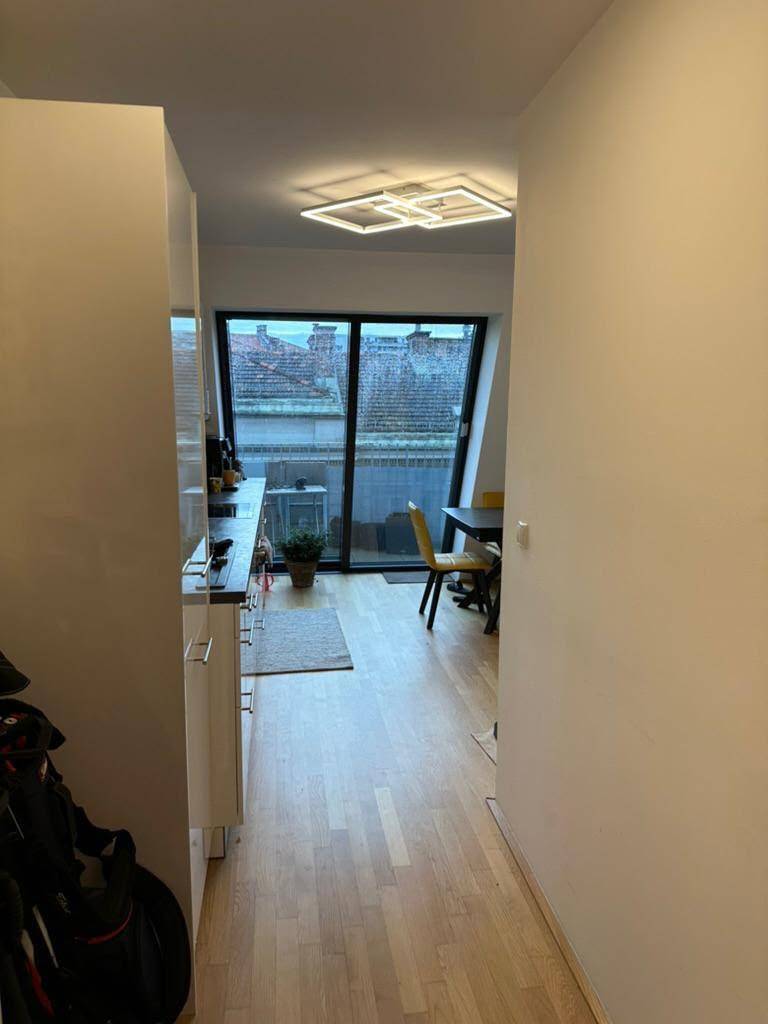Langer Flur mit Holzboden, der zur Küche und einem Essbereich mit Terrassenzugang führt.