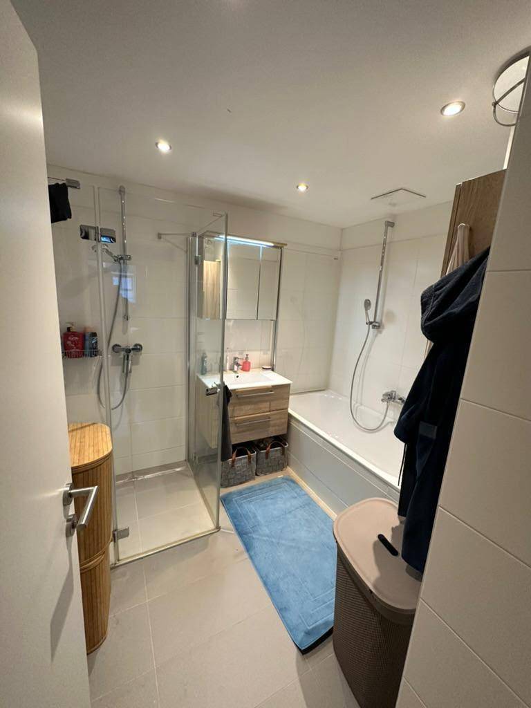 Modernes Badezimmer mit Glasdusche, Badewanne und Waschbecken mit praktischem Unterschrank.
