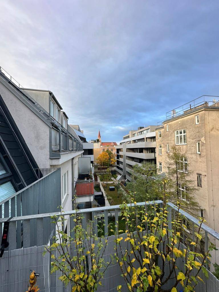 Balkon mit Blick auf einen begrünten Innenhof und die umliegende moderne Stadtarchitektur.