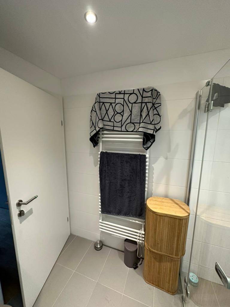 Badezimmer mit beheiztem Handtuchhalter und hellen Fliesen, bietet Komfort und Funktionalität.