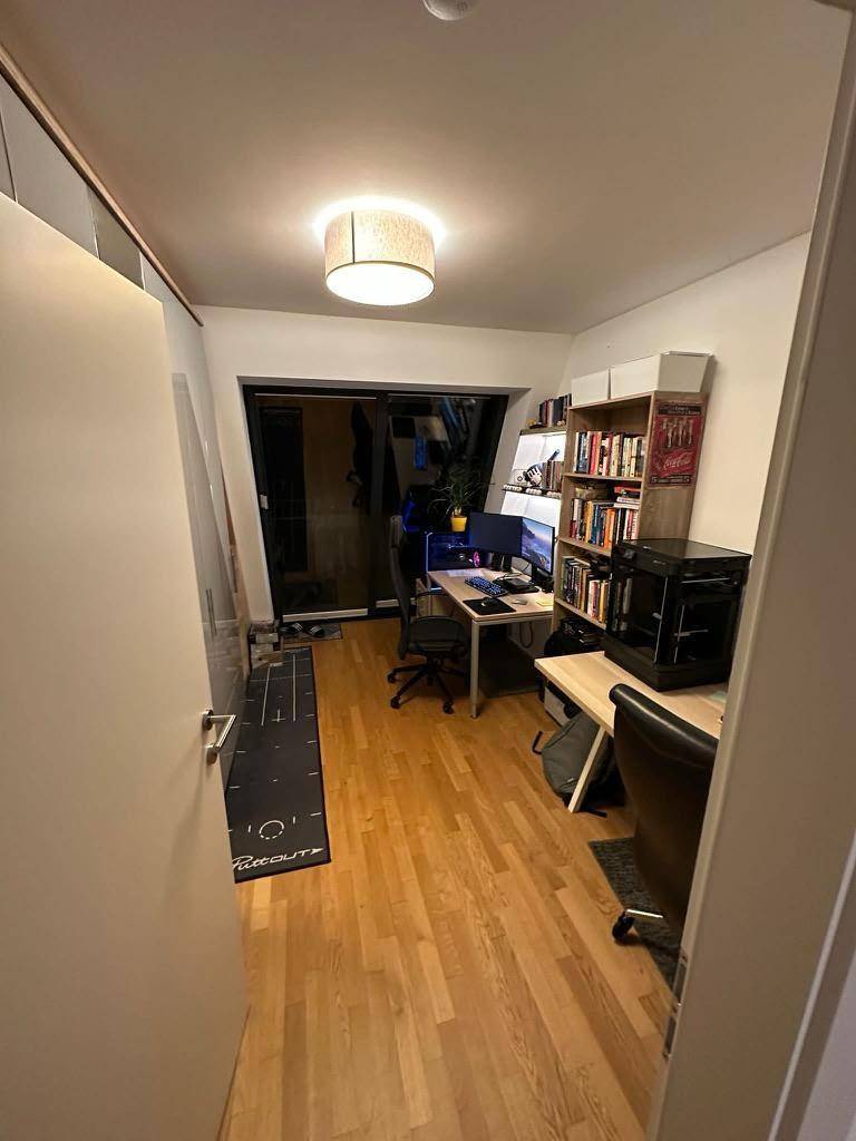 Helles Arbeitszimmer mit Holzboden, Bücherregalen und großem Fenster im Dachgeschoss.