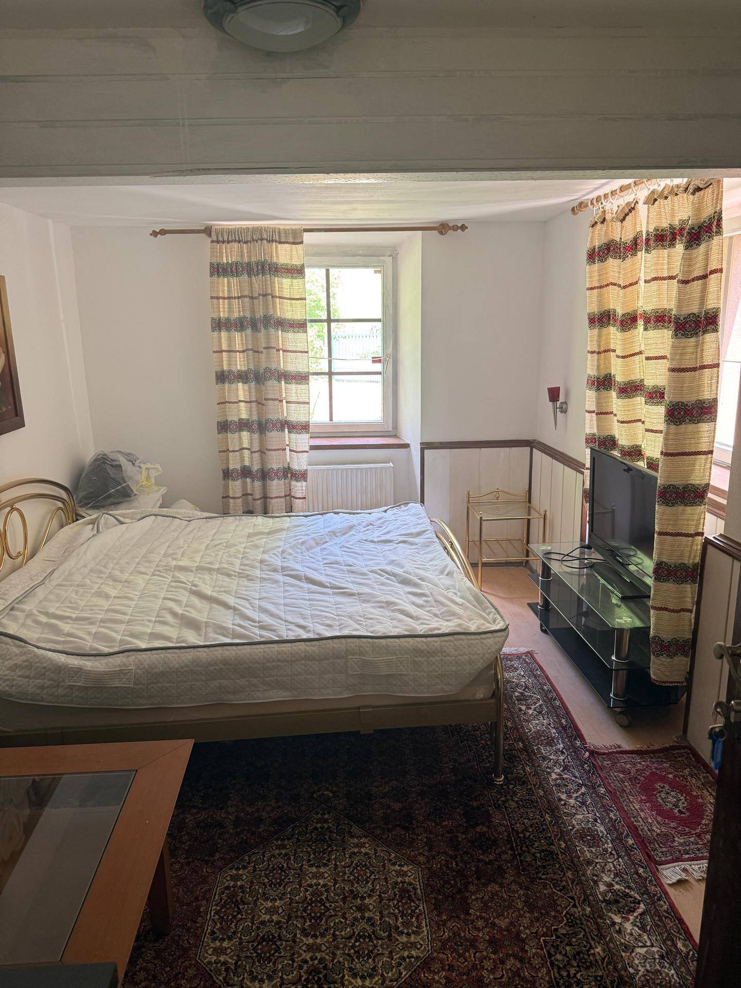 Gemütliches Schlafzimmer mit Doppelbett, Teppichboden und einem Fenster mit Vorhängen.