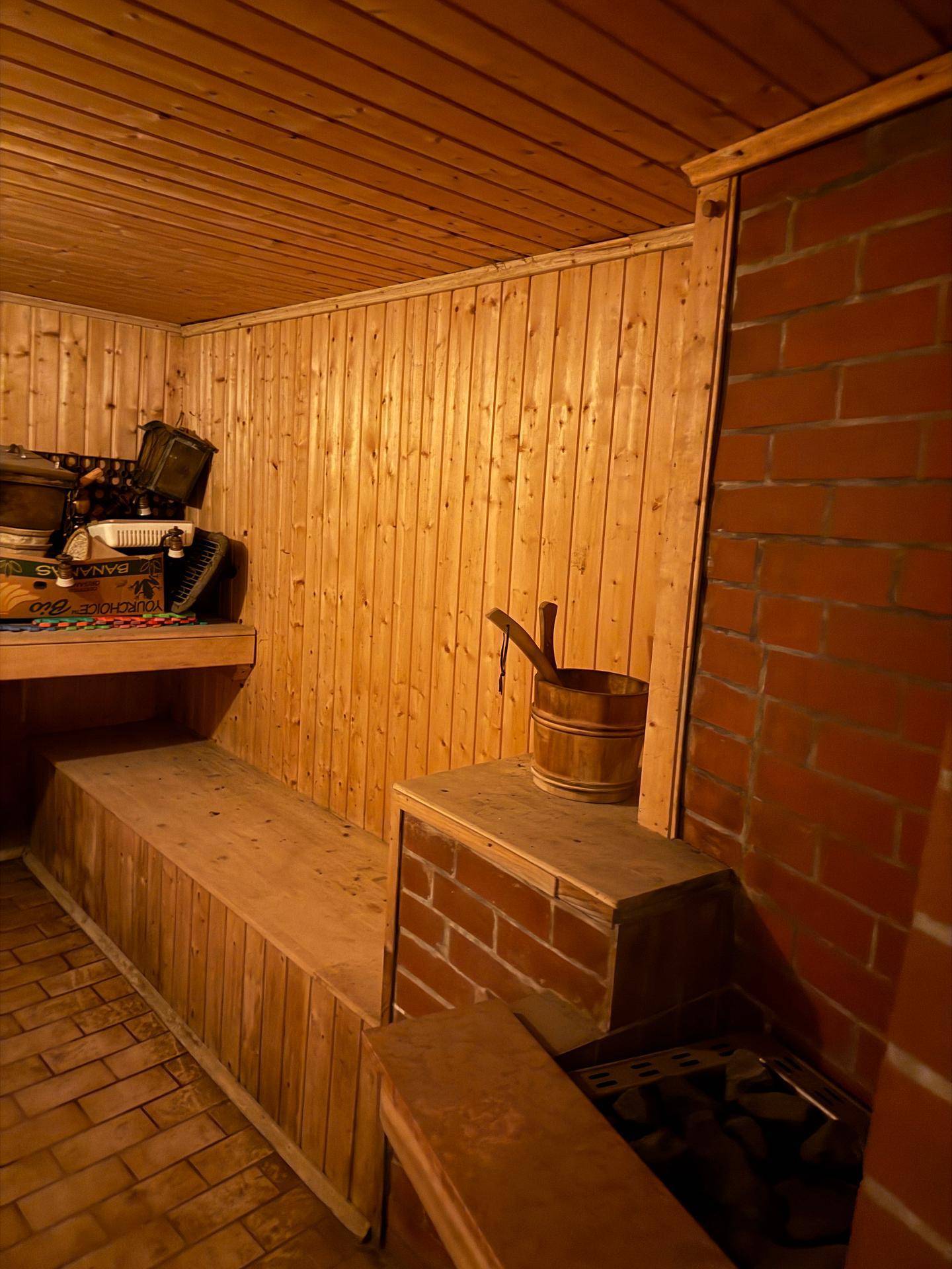 Traditionelle Holzsauna mit gemauertem Ofen und Holzeimer, bereit zur Nutzung.