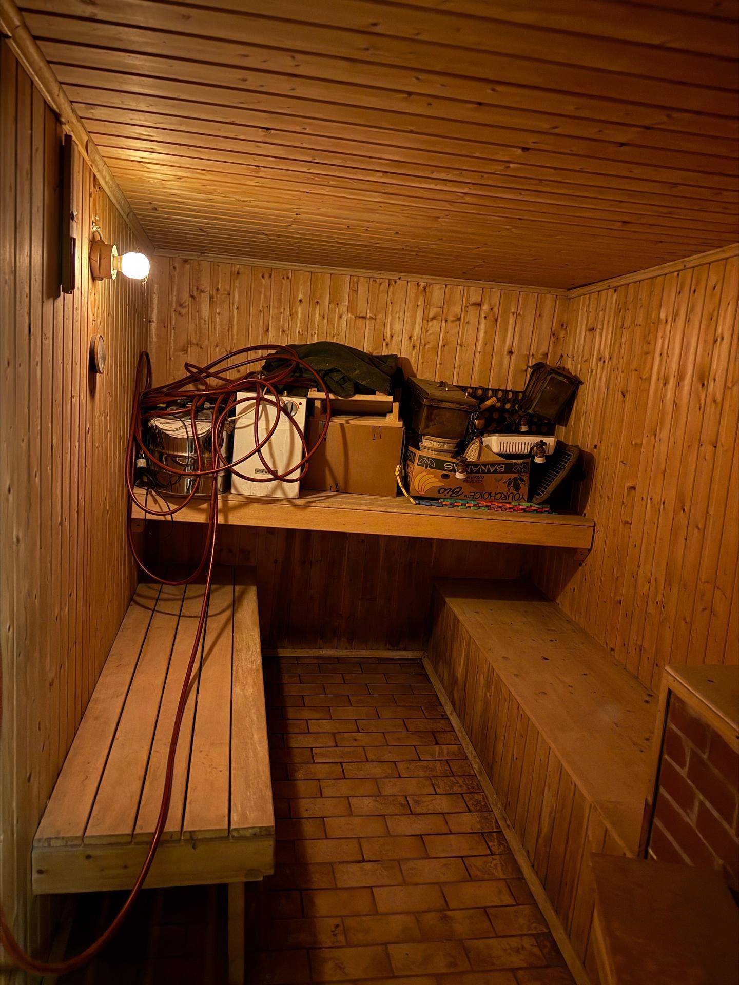 Holzvertäfelte Sauna mit Bänken und Zubehör, die derzeit als Lagerraum genutzt wird.