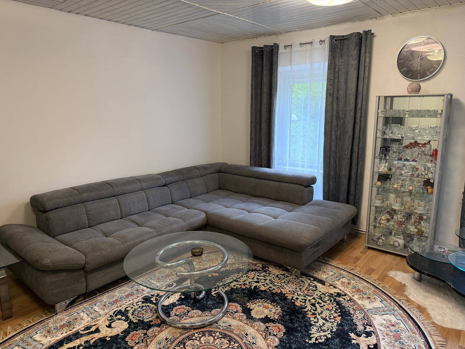 Geräumiges Wohnzimmer mit großem Ecksofa, Couchtisch und einem dekorativen Teppich.