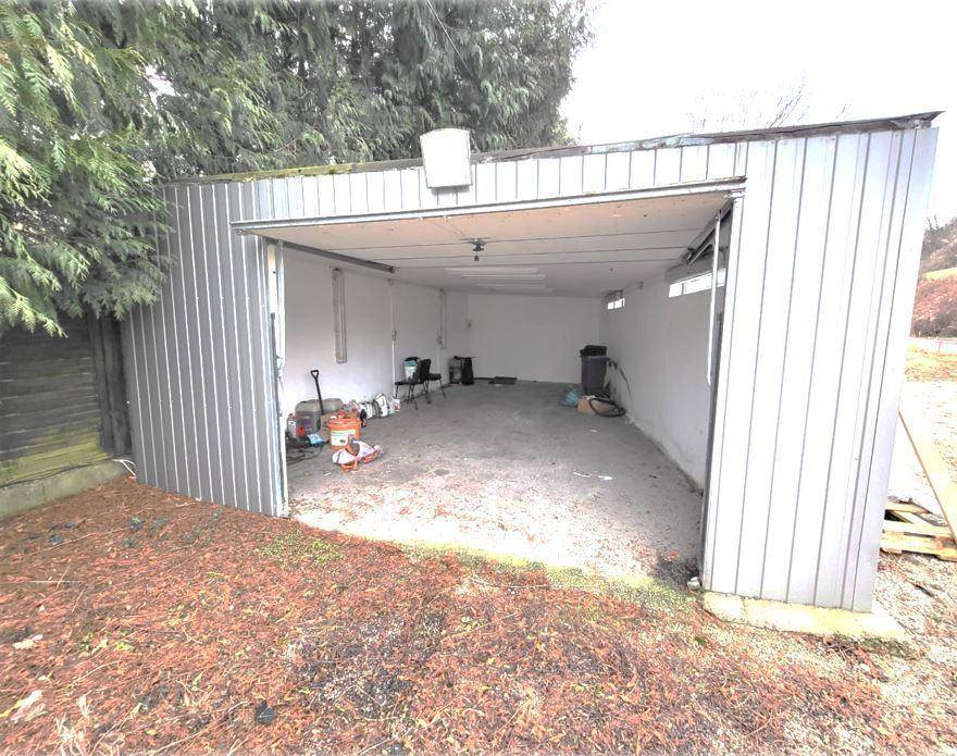 Innenansicht einer geräumigen Metallgarage mit Betonboden und einigen gelagerten Gegenständen.