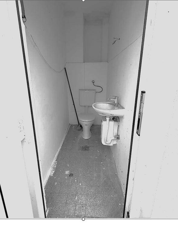 Kleiner Toilettenraum in Schwarz-Weiß mit WC und Waschbecken, einfach und funktional ausgestattet.