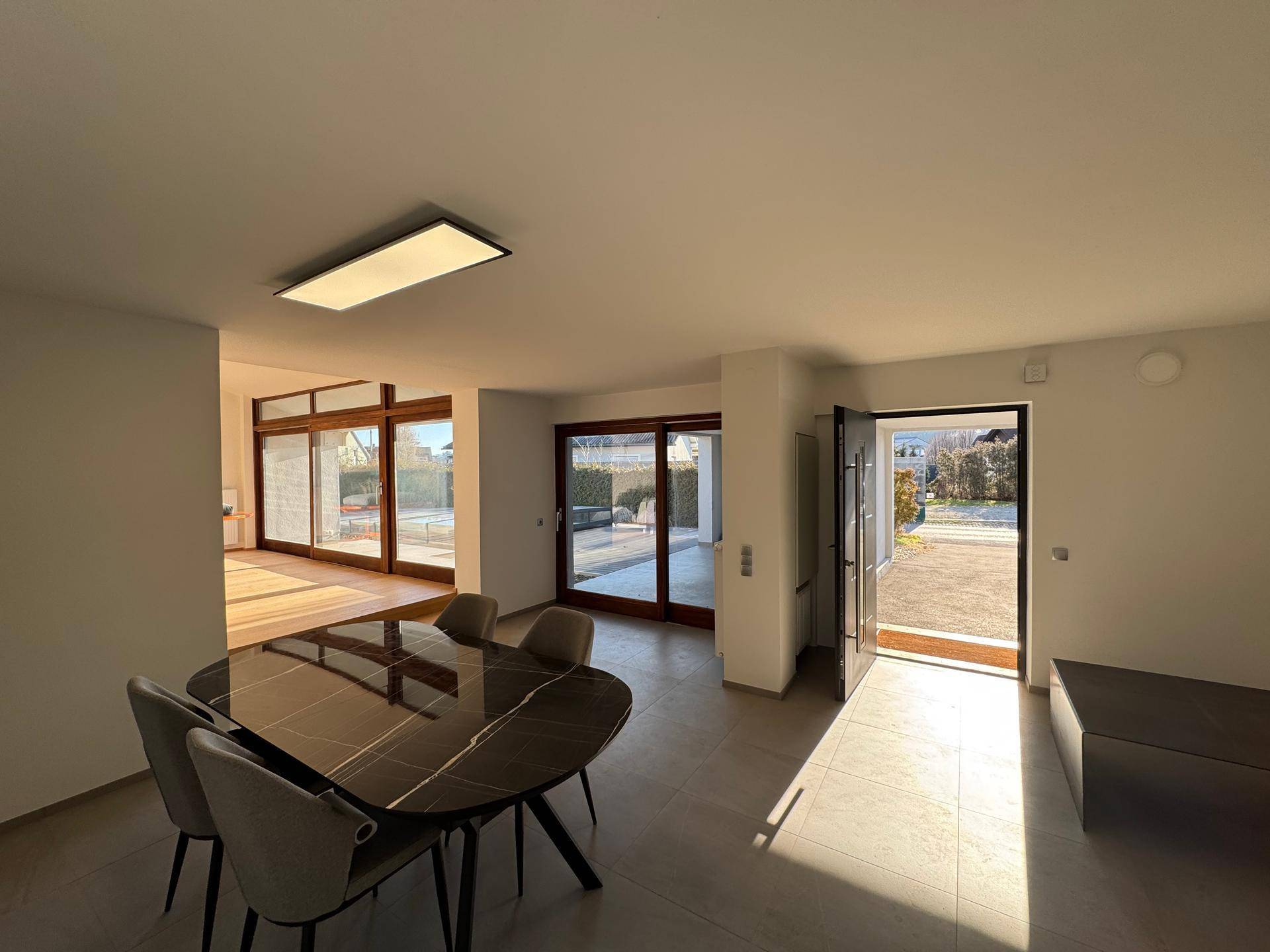 Heller Essbereich mit modernem Esstisch und direktem Zugang zu den Terrassenbereichen im Freien.