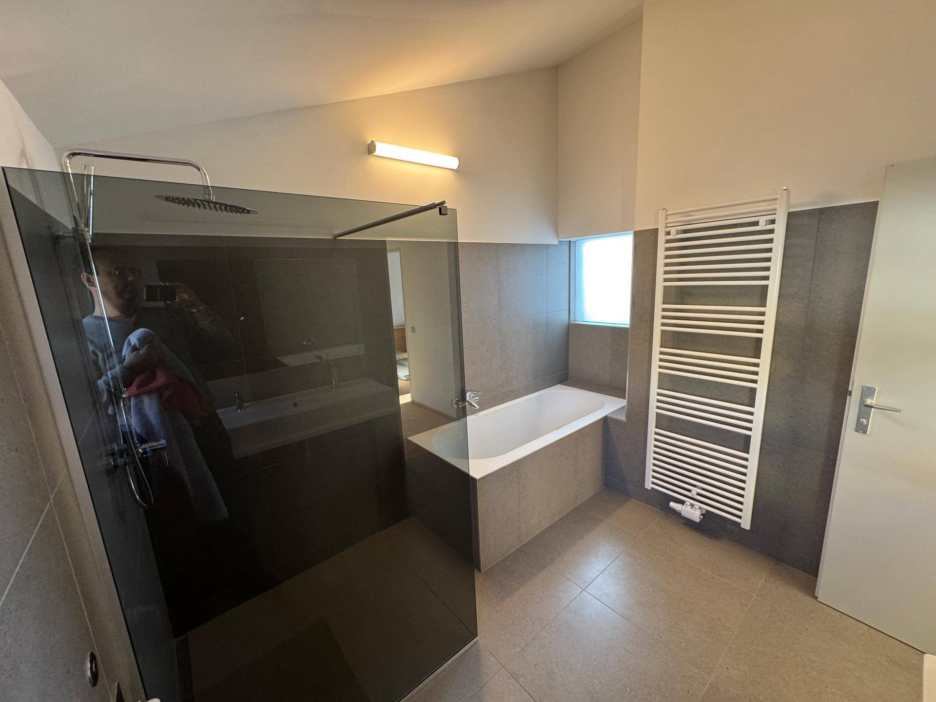 Modernes Badezimmer mit begehbarer Dusche, Badewanne und praktischem Handtuchheizkörper.