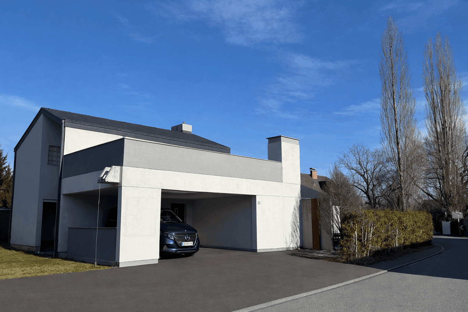 Vorderansicht des modernen Hauses mit integriertem Carport und gepflegter Einfahrt.