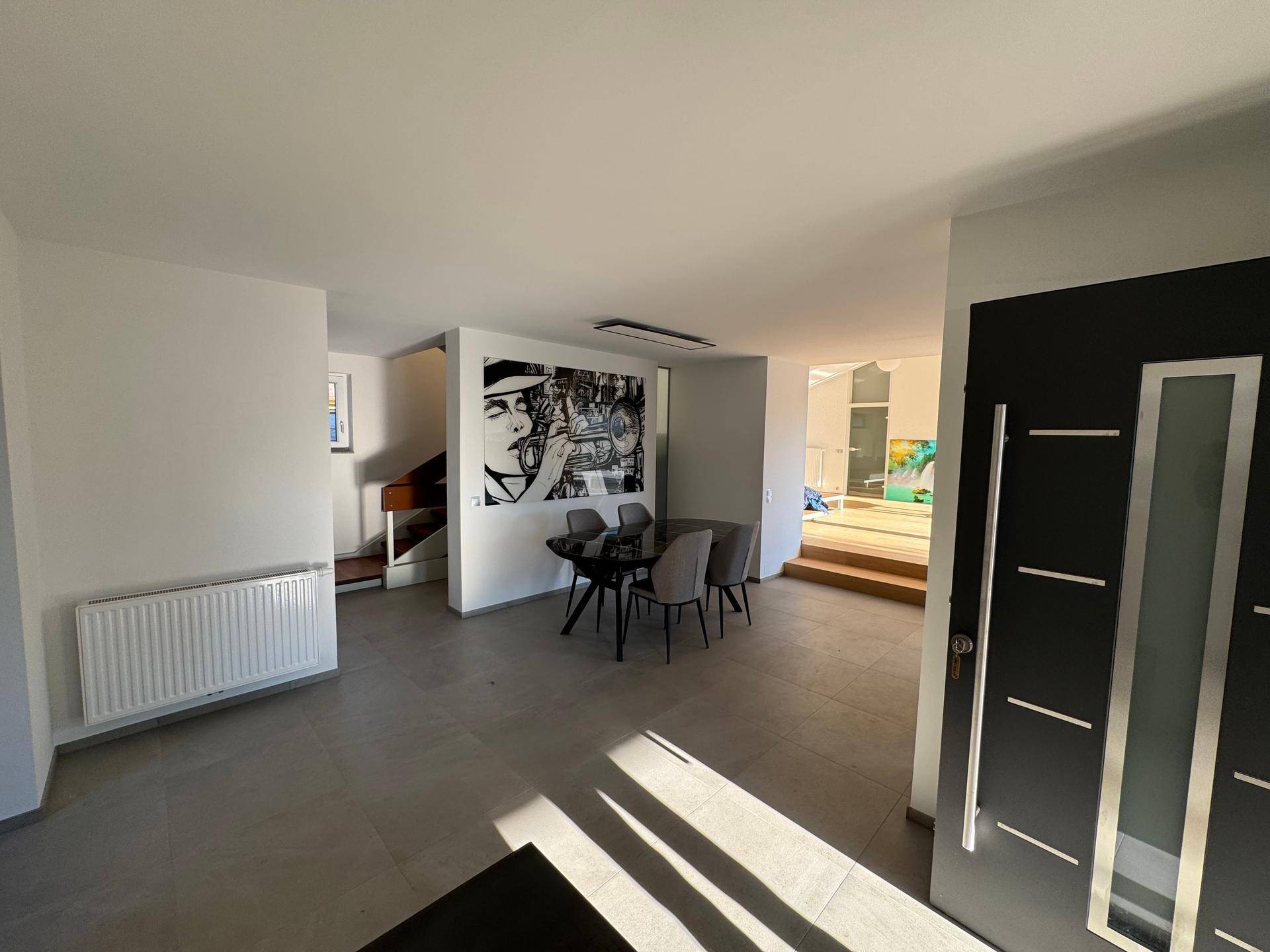 Geräumiger Essbereich mit modernem Tisch und Kunstwerk, offen zum Wohnbereich.