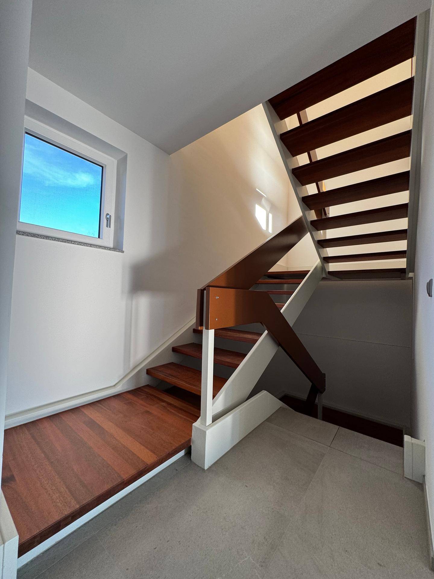 Moderne Holztreppe mit elegantem Geländer, die die verschiedenen Etagen verbindet.