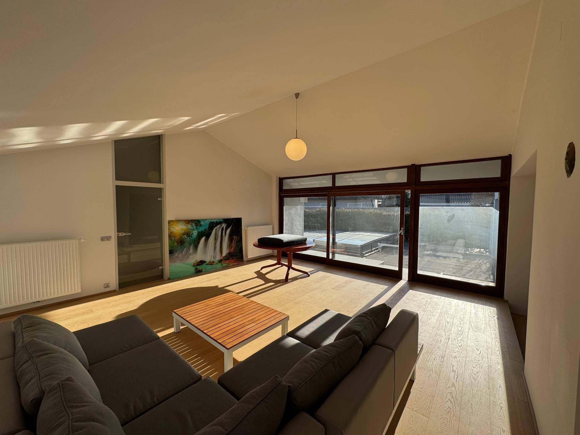 Heller Wohnbereich mit gemütlichem Sofa, Holzboden und Zugang zur Terrasse.