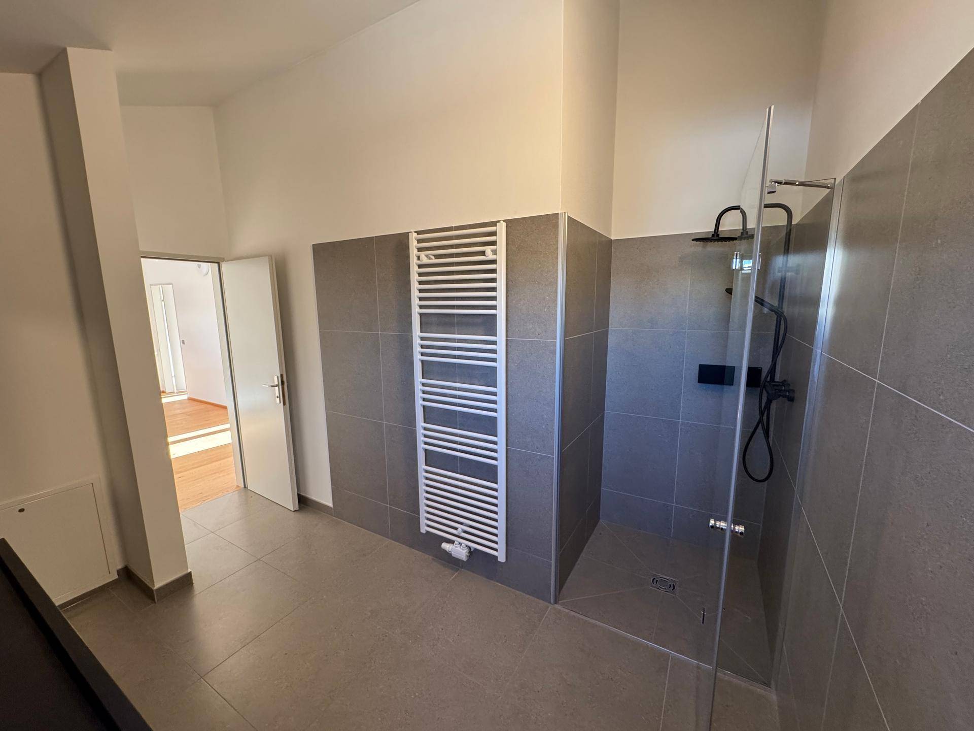 Modernes Badezimmer mit geräumiger Dusche und praktischem Handtuchheizkörper.