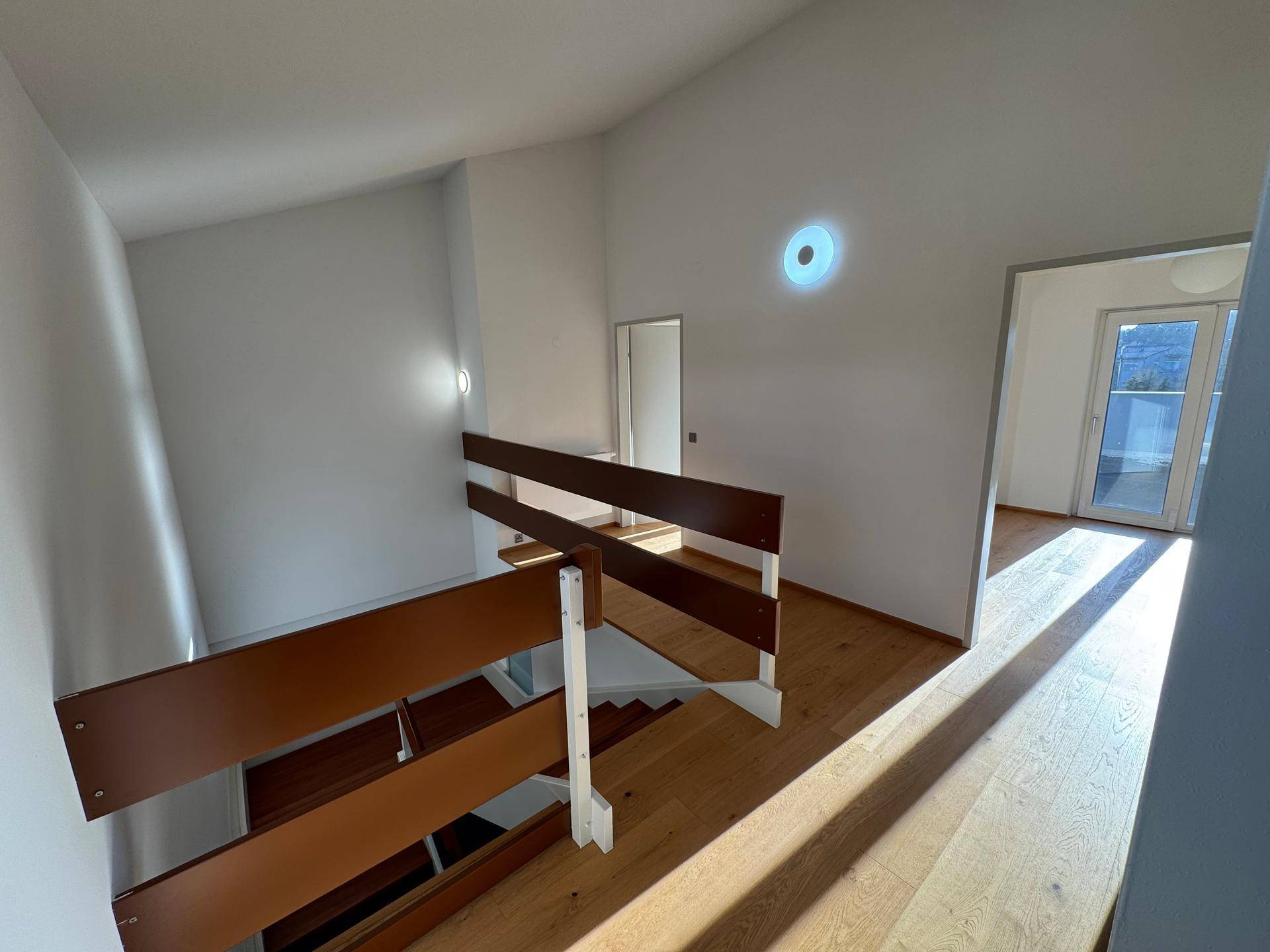 Heller Flur im Obergeschoss mit Holzboden und Blick ins offene Treppenhaus.