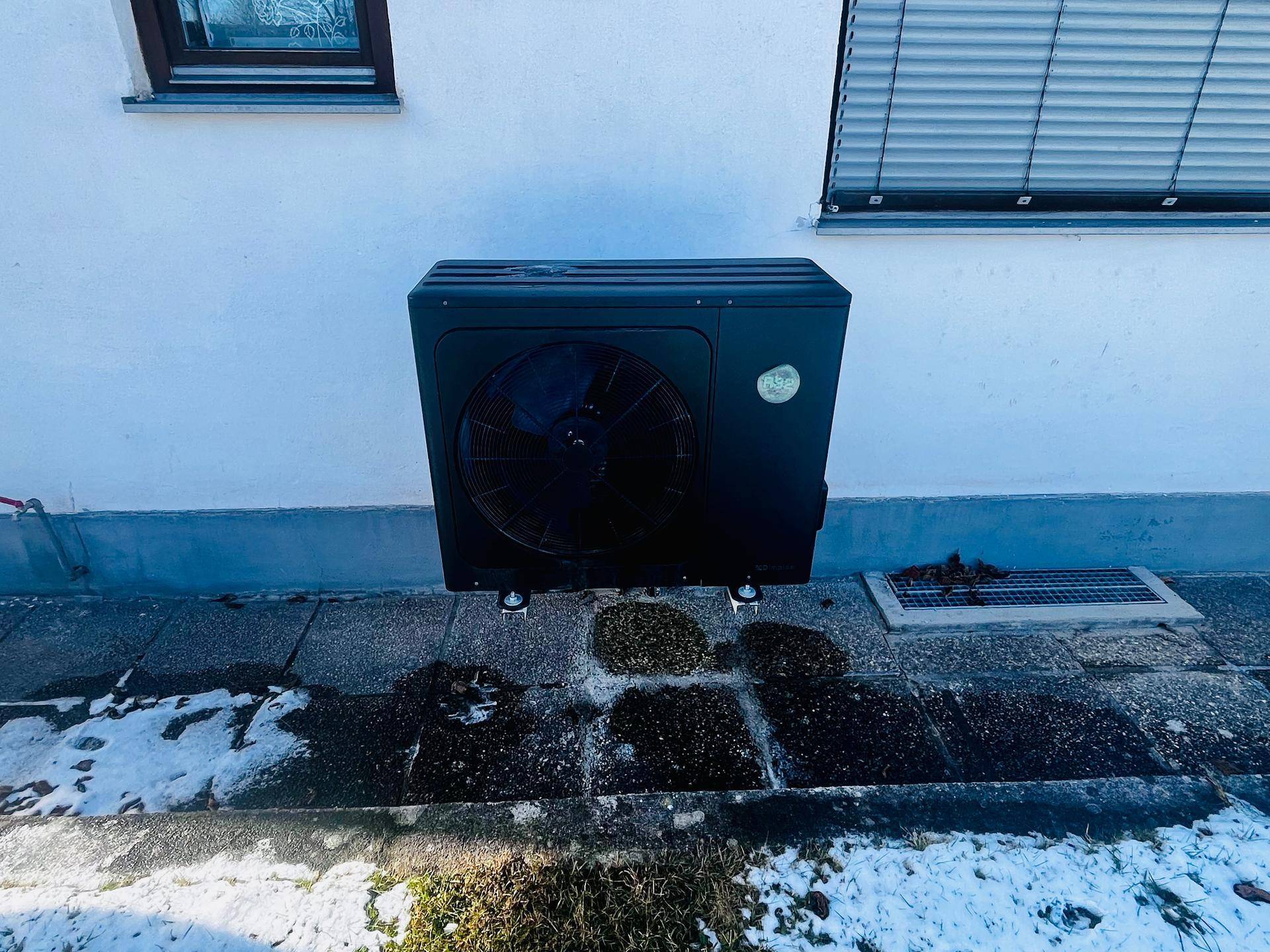 Außenansicht einer modernen schwarzen Wärmepumpe an der Hauswand installiert.