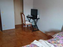 Schlafzimmer mit Parkettboden, kleinem Schreibtisch und Stuhl.