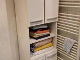 Badezimmerschrank mit Handtüchern und einem beheizten Handtuchhalter.