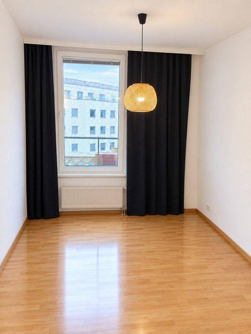 Helles, unmöbliertes Schlafzimmer mit Parkettboden und großem Fenster, bereit zur Einrichtung.