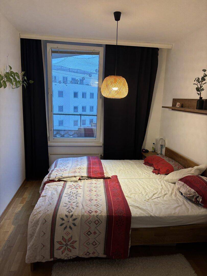 Gemütliches Schlafzimmer mit Doppelbett, Parkettboden und Blick aus dem Fenster, weihnachtlich dekoriert.
