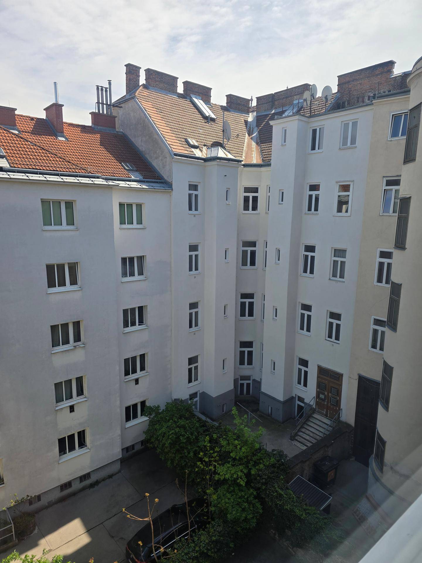 Blick auf einen begrünten Innenhof, umgeben von traditionellen Wiener Altbauten.