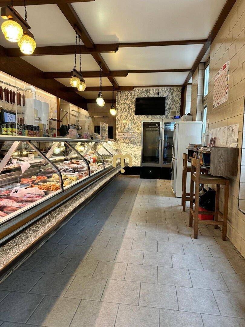 Innenansicht eines Ladengeschäfts mit langer Verkaufstheke, gefüllt mit Fleisch- und Wurstwaren.
