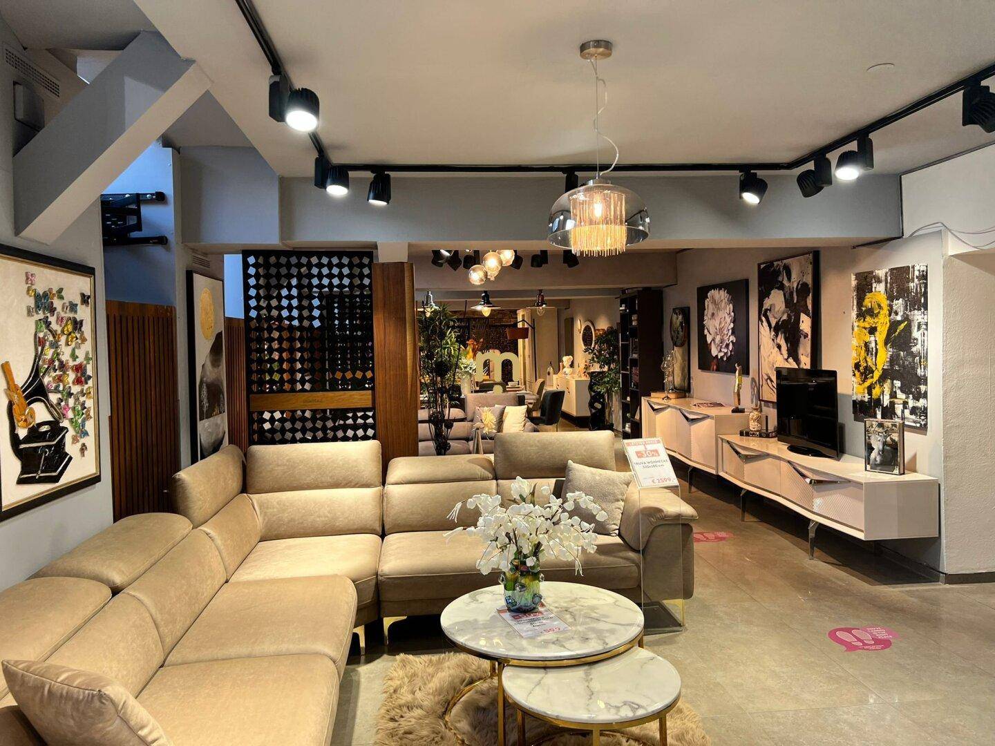 Heller Wohnbereich mit beigem Ecksofa, runden Couchtischen und moderner Beleuchtung.