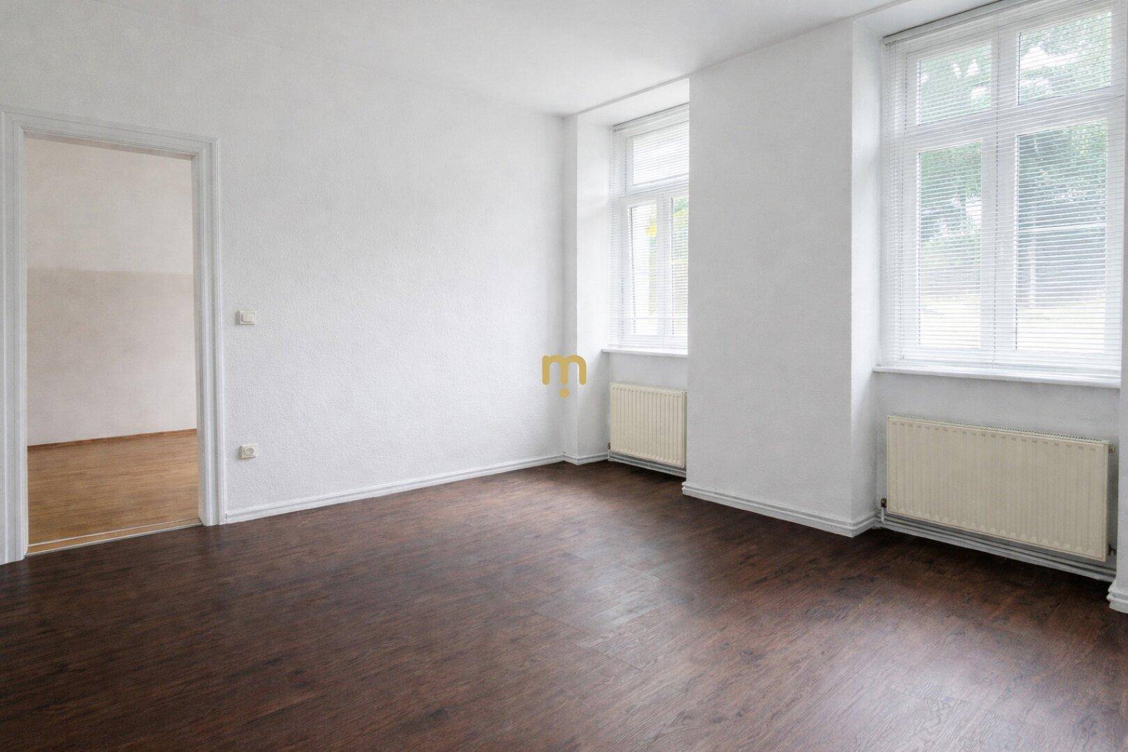 Geräumiges, helles Zimmer mit Laminatboden und Blick auf die Umgebung durch zwei Fenster.