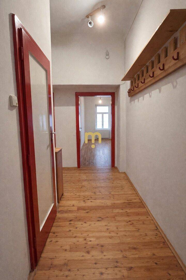 Langer Flur mit Holzboden und roten Türen, der zu weiteren Räumen führt.