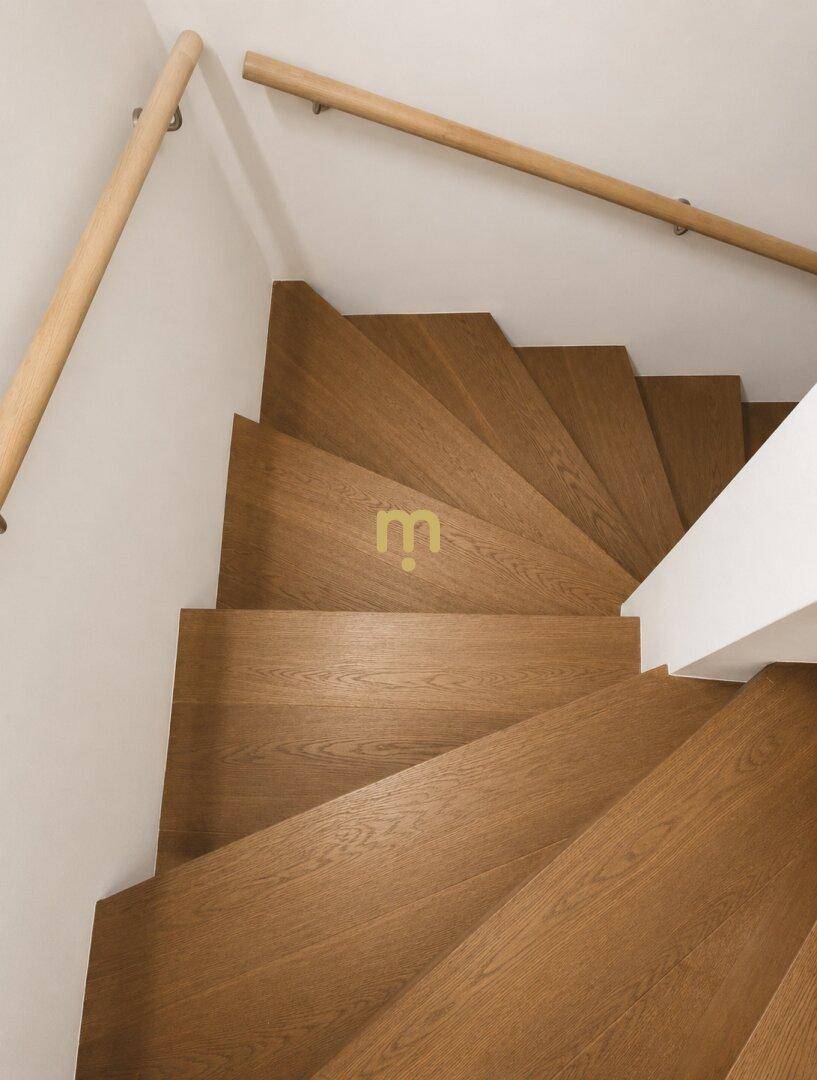 Elegante Holztreppe mit Handläufen, die verschiedene Etagen des Hauses stilvoll verbindet.