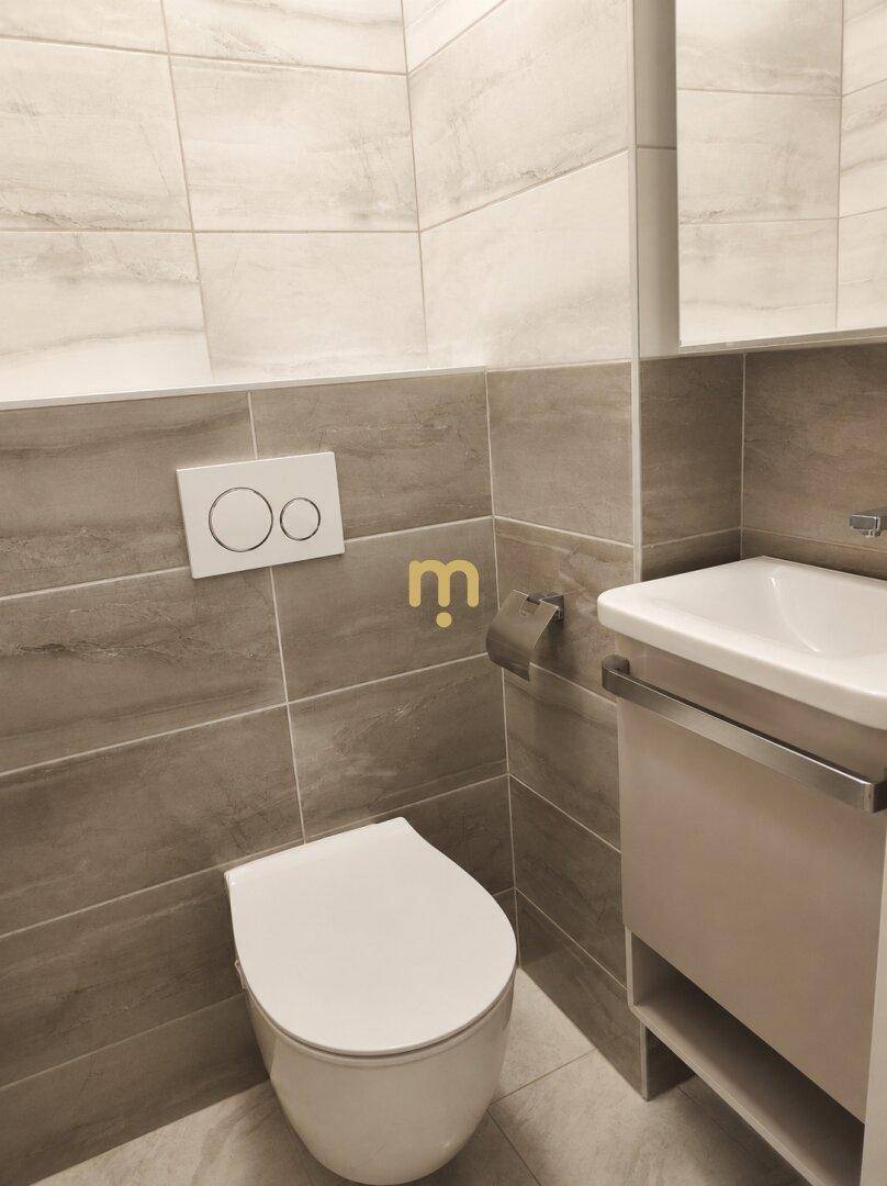 Modernes Gäste-WC mit Wand-WC, kleinem Waschbecken und grauen Fliesen an den Wänden.