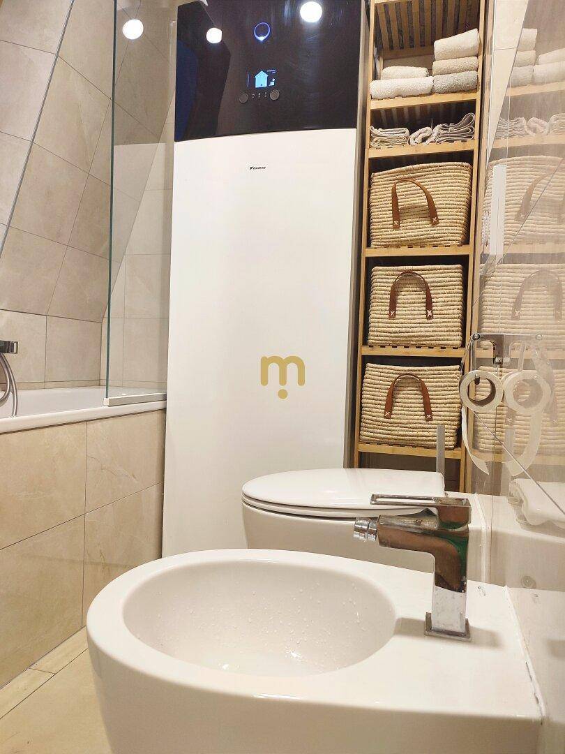 Modernes Badezimmer mit Bidet, WC, Badewanne und einer effizienten Wärmepumpe.