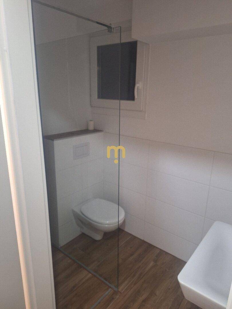Modernes Badezimmer mit begehbarer Dusche, wandhängendem WC und Fenster.