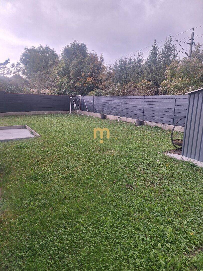 Großer, gepflegter Gartenbereich mit Rasenfläche, Zaun und Gartenhaus.
