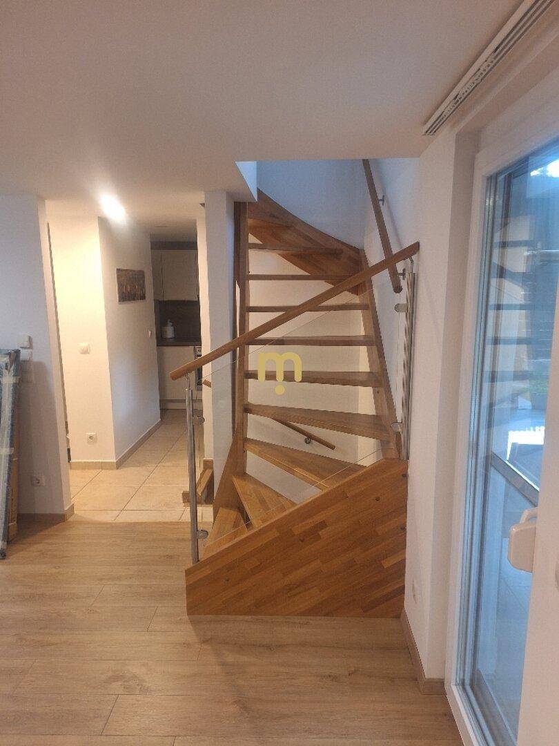 Helle Holztreppe mit Metallgeländer führt in den oberen Bereich des Hauses.