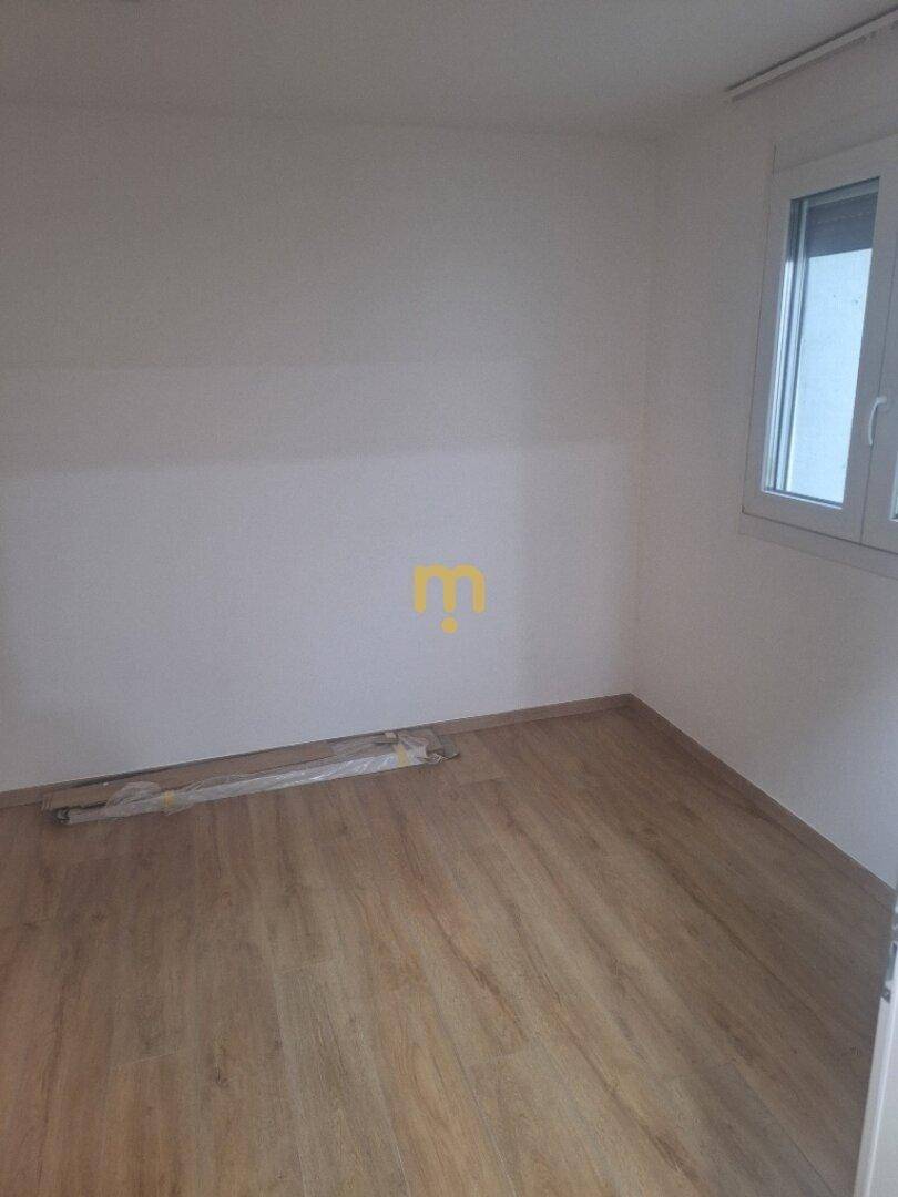 Helles Schlafzimmer mit Laminatboden und großem Fenster für viel Tageslicht.