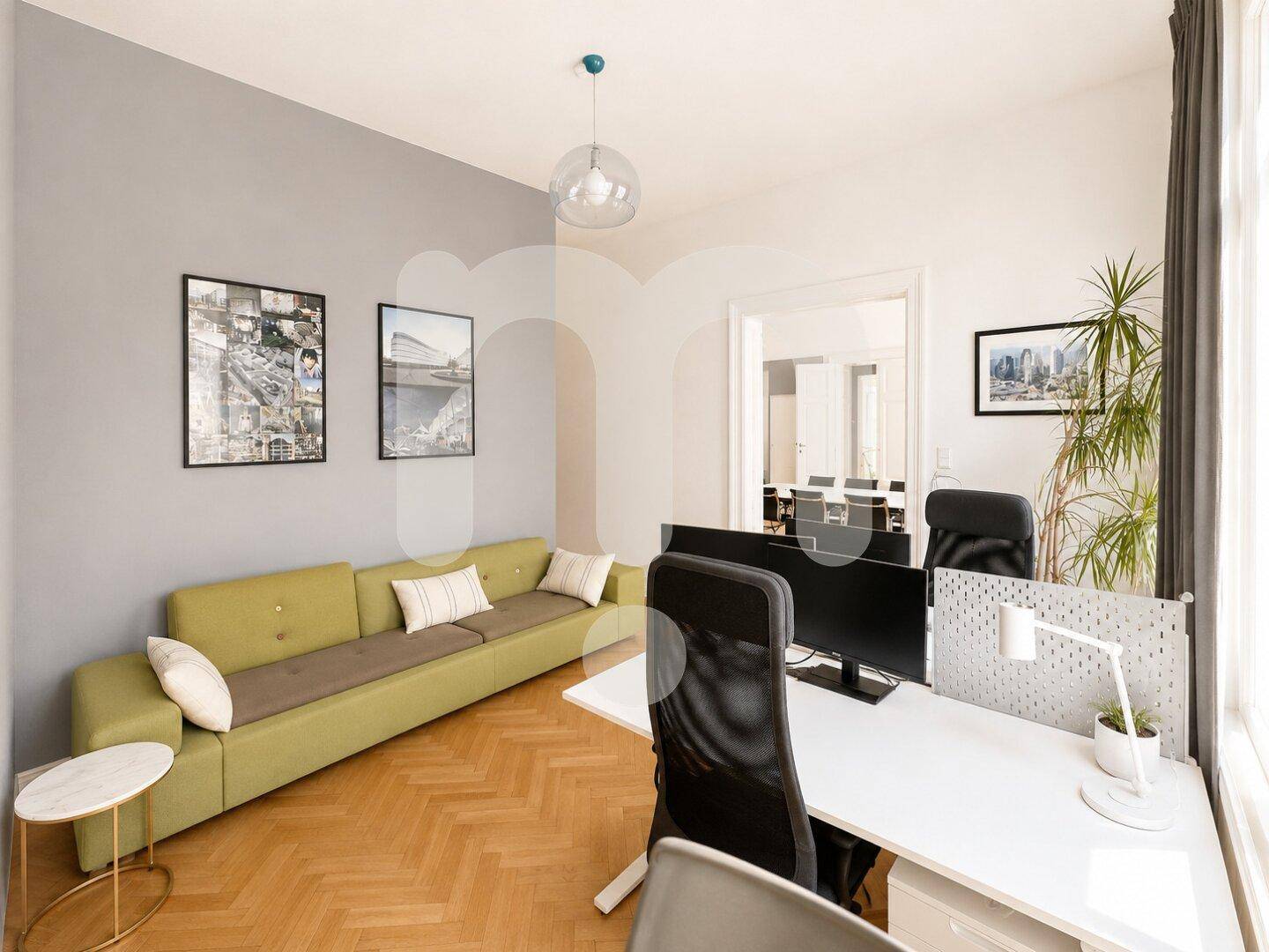 Gemütlicher Bürobereich mit langem grünem Sofa, Schreibtisch und Computer, ideal für entspanntes Arbeiten.