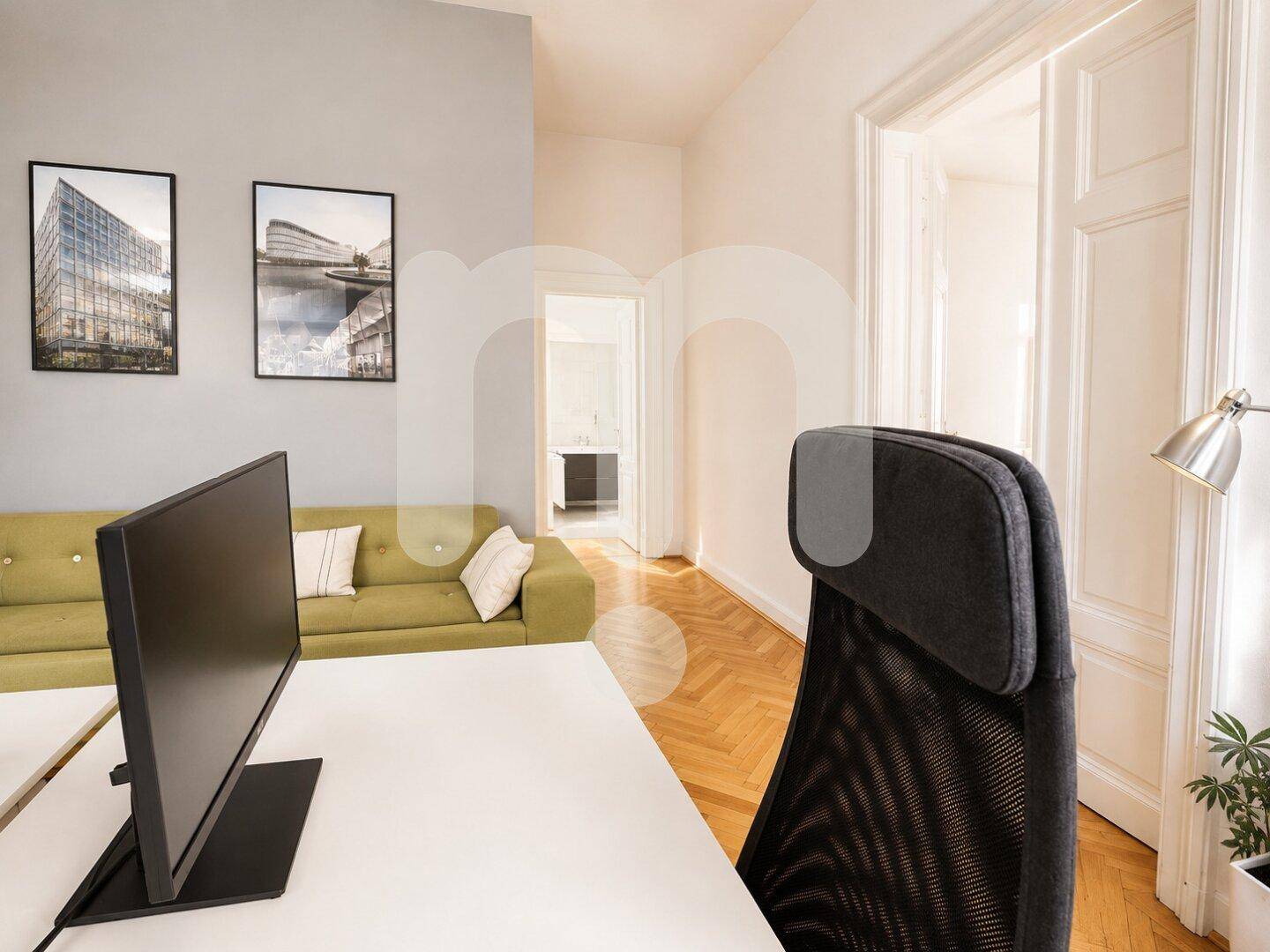 Büroarbeitsplatz mit Schreibtisch, Computer und Blick in einen angrenzenden Raum, mit Parkettboden.