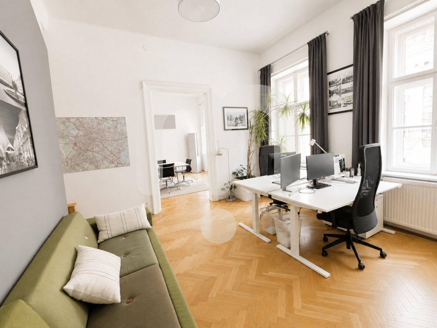 Offener Bürobereich mit Schreibtischen, grünem Sofa und Blick in den angrenzenden Konferenzraum.