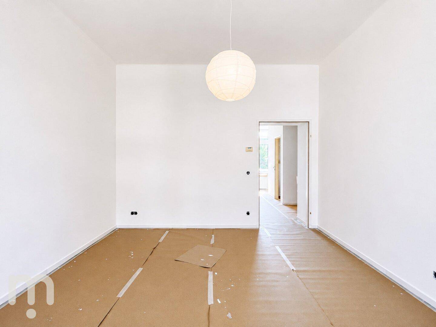 Helles Zimmer mit einem Fenster und Blick in einen weiteren Raum, Boden für Verlegung vorbereitet.