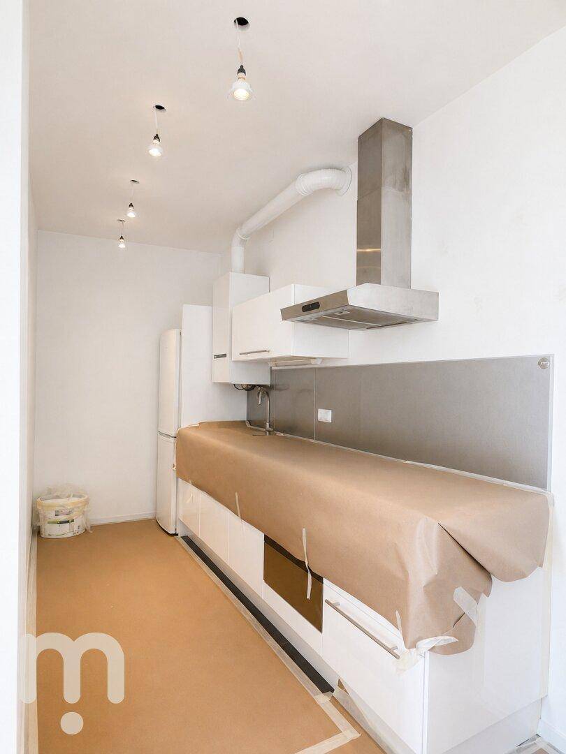 Küche mit moderner Dunstabzugshaube und vorbereiteten Arbeitsflächen, bereit für die Fertigstellung.