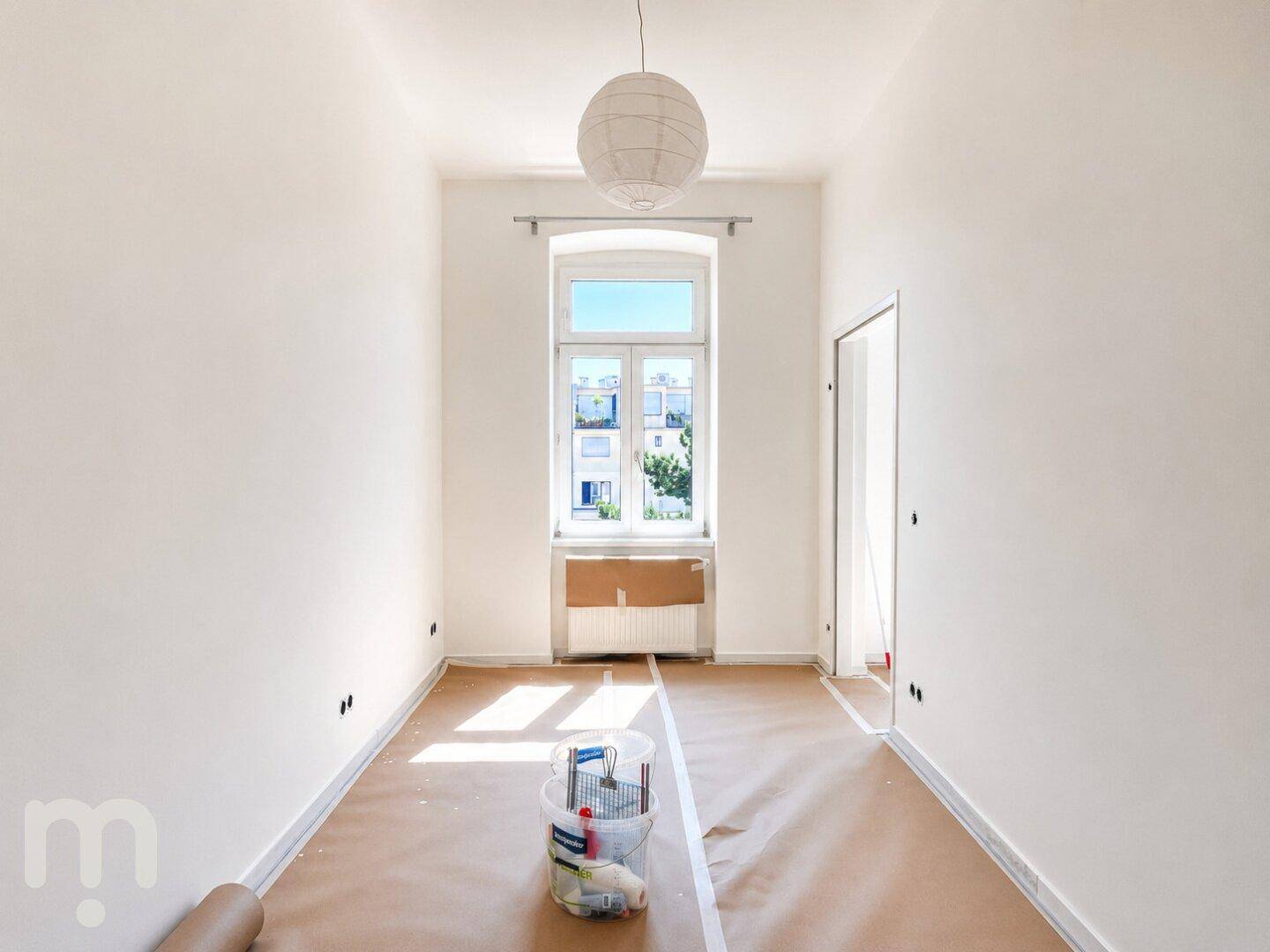 Helles Zimmer mit einem großen Fenster und Renovierungsmaterialien, bereit zur Fertigstellung.