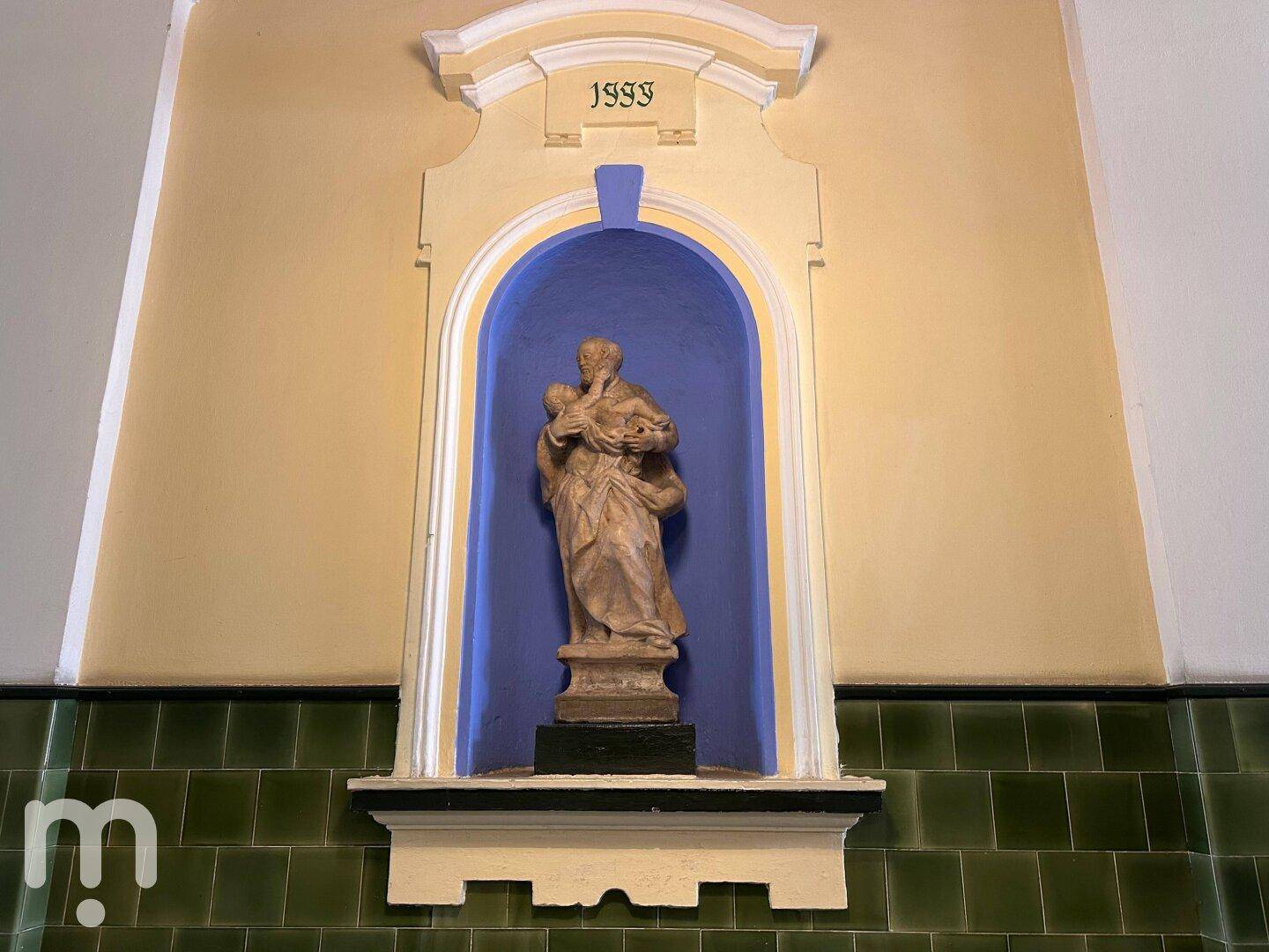 Eine dekorative Wandnische mit einer Statue und grünen Fliesen in einem historischen Gebäude.