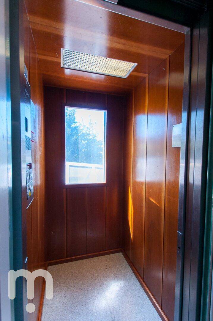 Ein Aufzug mit Holzverkleidung und einem kleinen Fenster, das natürliches Licht hereinlässt.
