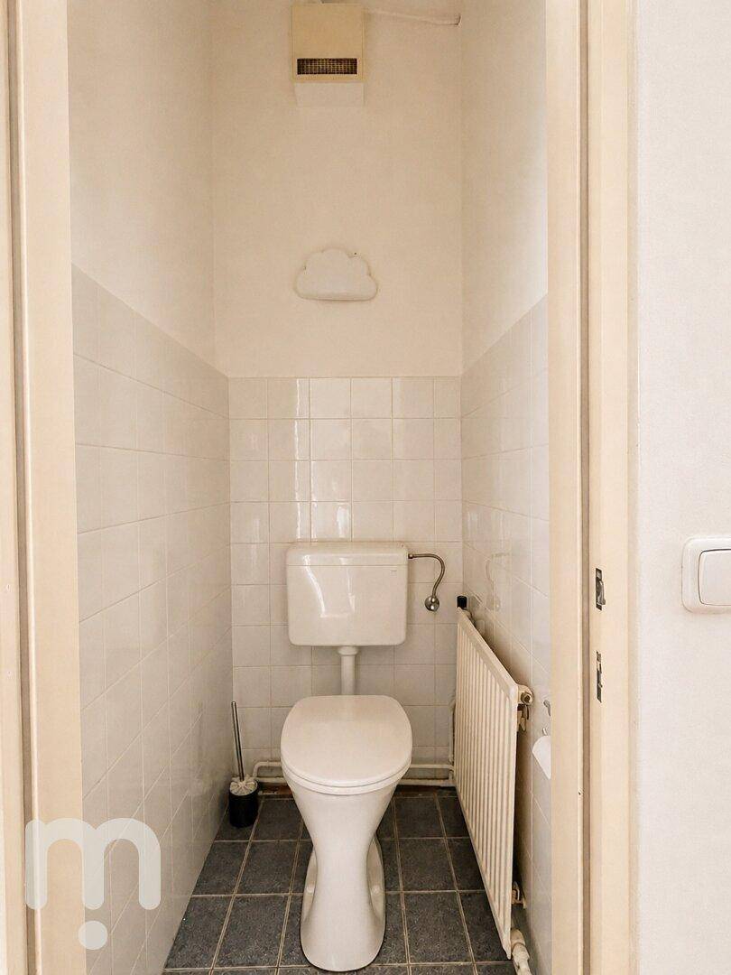 Separates WC mit Fliesenboden, Toilette und Heizkörper, einfach und funktional.